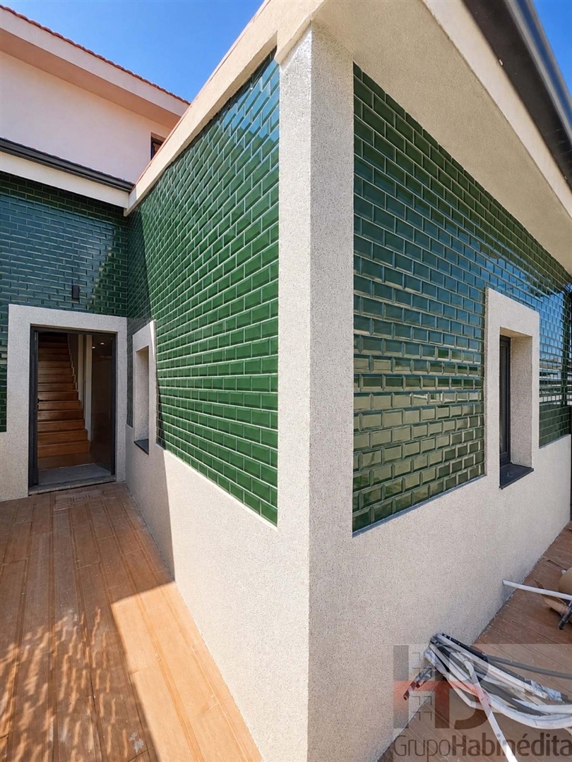 Pátio junto à fachada em azulejo verde